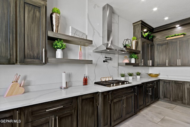 kitchen featuring light stone counters, dark brown cabinetry, range hood, and stainless steel gas cooktop