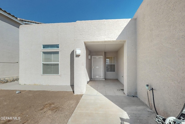 entrance to property featuring a patio area and stucco siding