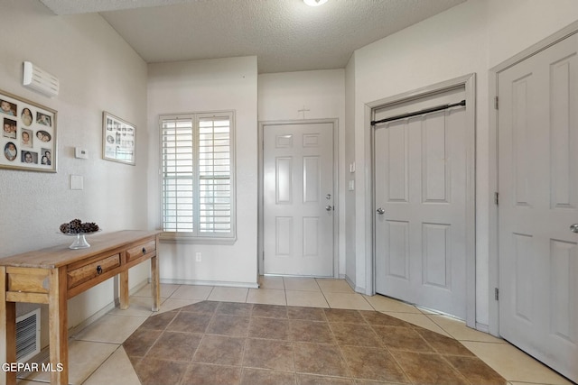 foyer with light tile patterned floors and a textured ceiling