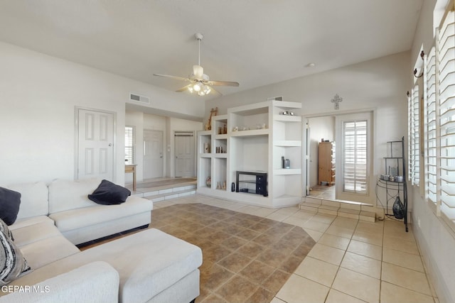 tiled living room featuring built in shelves and ceiling fan