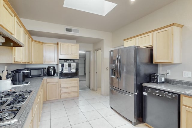 kitchen with a skylight, light tile patterned floors, light brown cabinetry, and black appliances