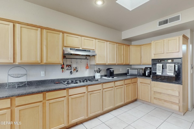 kitchen with light brown cabinets, black oven, and a skylight