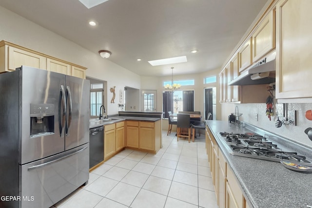 kitchen with a skylight, stainless steel appliances, hanging light fixtures, a sink, and under cabinet range hood