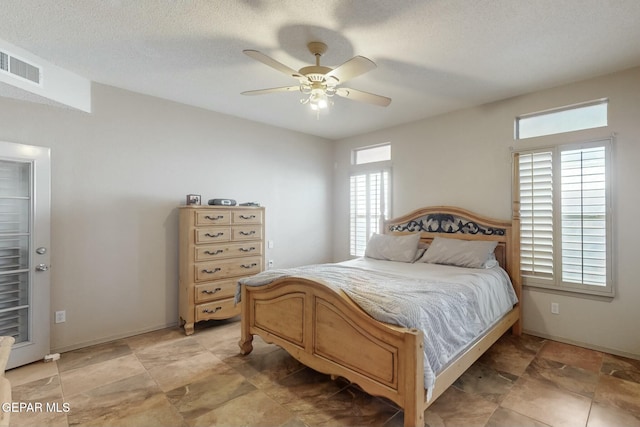 bedroom featuring baseboards, visible vents, ceiling fan, and a textured ceiling