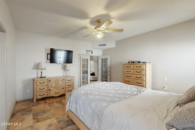 bedroom featuring stone finish floor, visible vents, ceiling fan, and baseboards