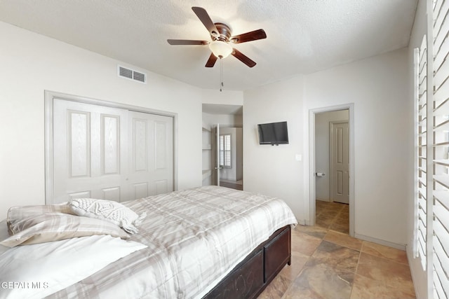 bedroom with a textured ceiling, a closet, visible vents, and a ceiling fan