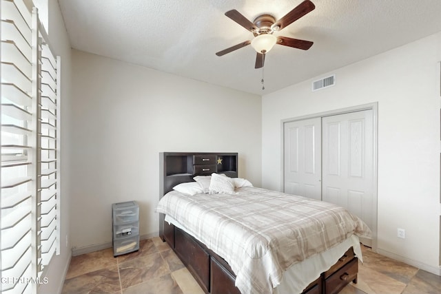 bedroom with a textured ceiling, a ceiling fan, visible vents, baseboards, and a closet