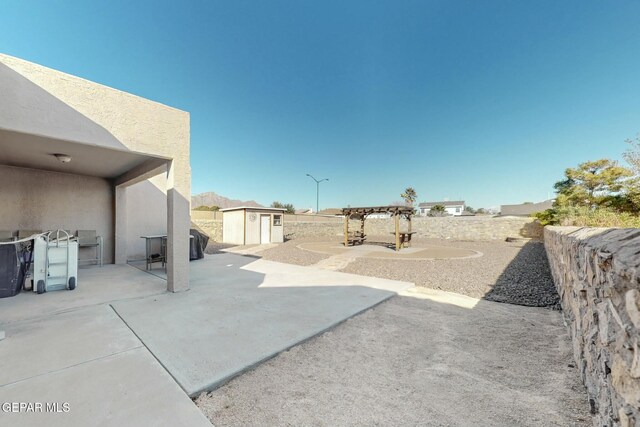 view of patio / terrace featuring a fenced backyard, a storage unit, a pergola, and an outdoor structure