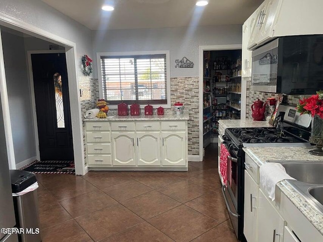 kitchen featuring white cabinetry, dark tile patterned flooring, and stainless steel gas range oven