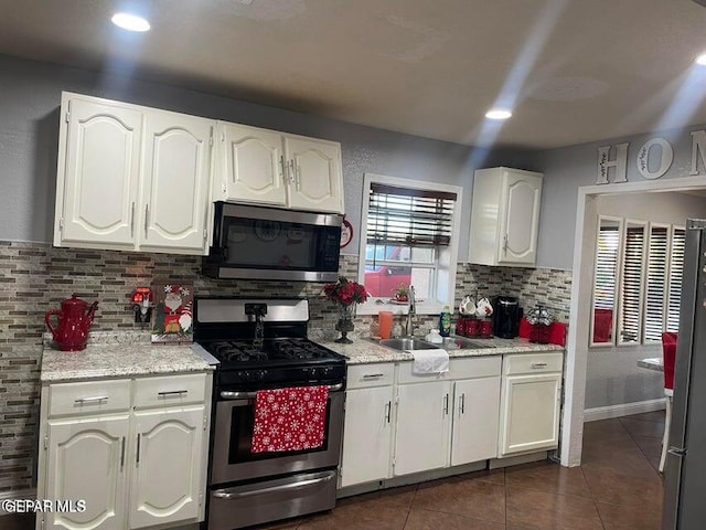 kitchen featuring white cabinetry, appliances with stainless steel finishes, sink, and dark tile patterned flooring