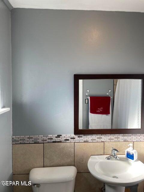 bathroom featuring tile walls, sink, and toilet