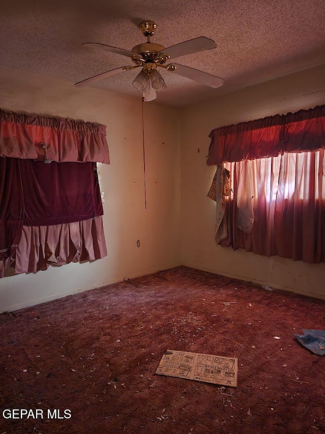 unfurnished room with ceiling fan and a textured ceiling