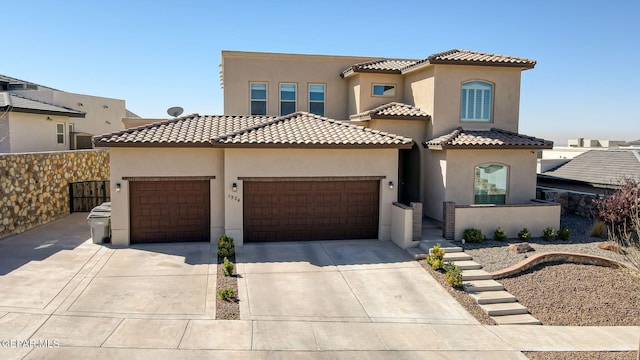 mediterranean / spanish-style home with a tiled roof, stucco siding, an attached garage, and concrete driveway