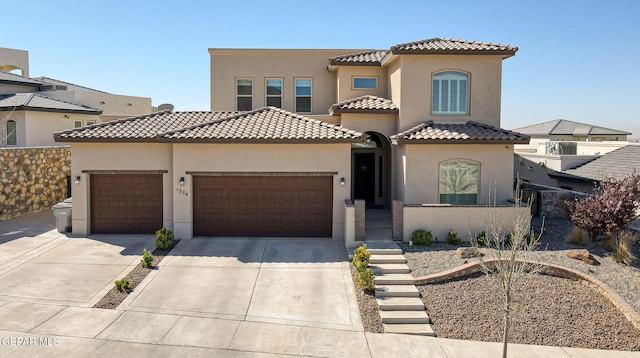 mediterranean / spanish-style home featuring stucco siding, an attached garage, a tile roof, and driveway