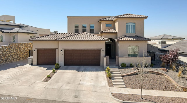 mediterranean / spanish house featuring stucco siding, driveway, an attached garage, and a tile roof