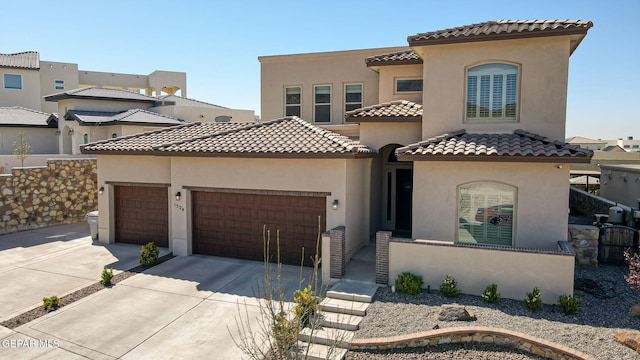 mediterranean / spanish-style house featuring a tiled roof, stucco siding, an attached garage, and driveway