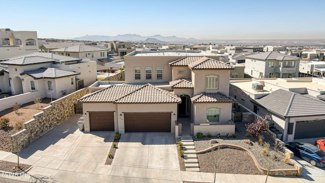 mediterranean / spanish-style house featuring stucco siding, a residential view, concrete driveway, a garage, and a tiled roof