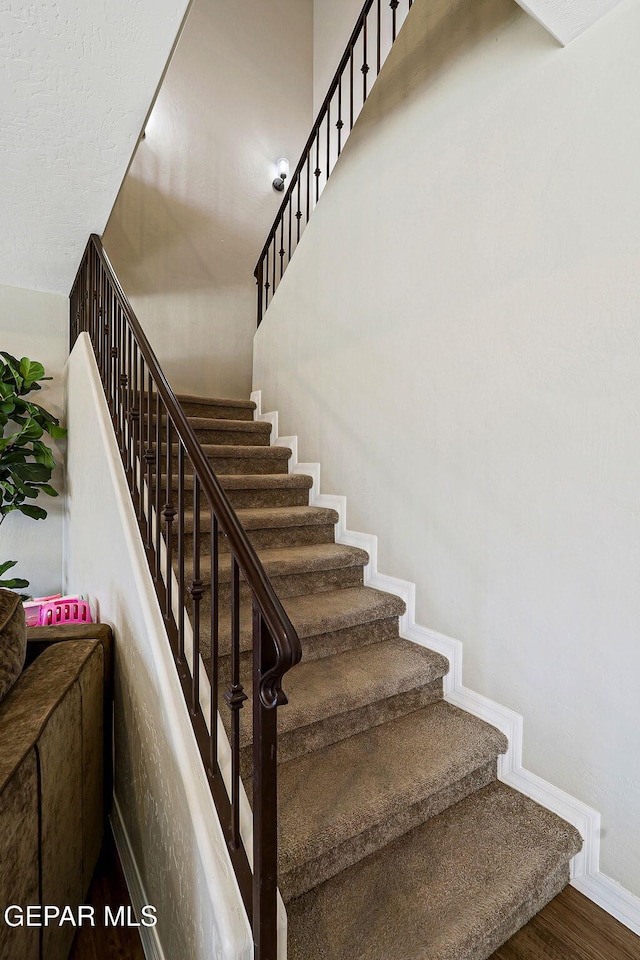 staircase featuring wood finished floors and baseboards