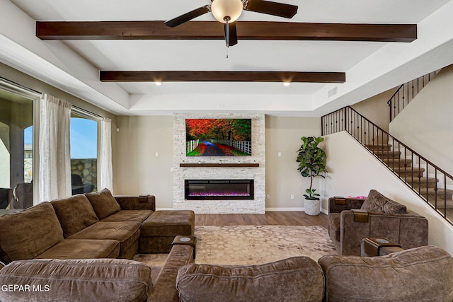 living room with a ceiling fan, wood finished floors, a fireplace, baseboards, and stairs