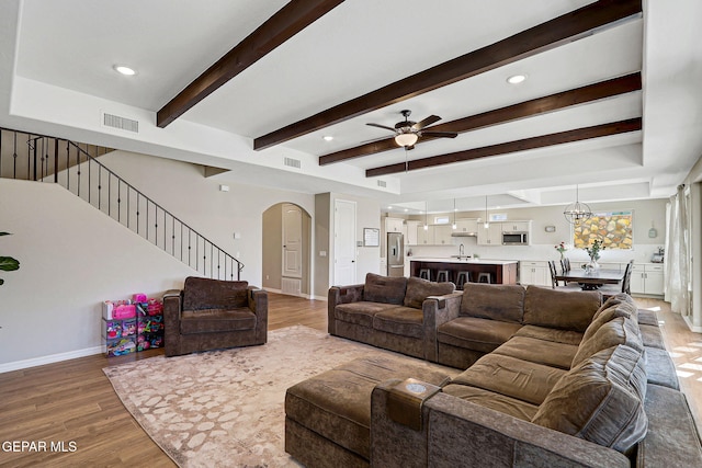 living area with arched walkways, visible vents, stairs, and wood finished floors