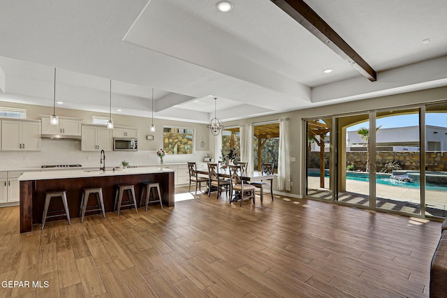 dining room with recessed lighting, a tray ceiling, beam ceiling, and wood finished floors