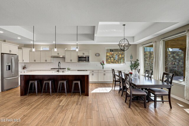 dining space with recessed lighting, a tray ceiling, a notable chandelier, and light wood-style flooring