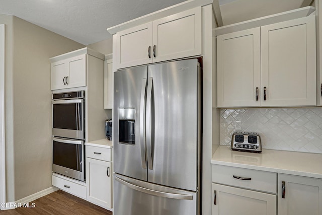 kitchen with baseboards, dark wood finished floors, light countertops, appliances with stainless steel finishes, and tasteful backsplash