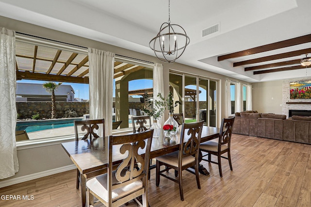 dining area featuring visible vents, light wood-style floors, a healthy amount of sunlight, and a fireplace