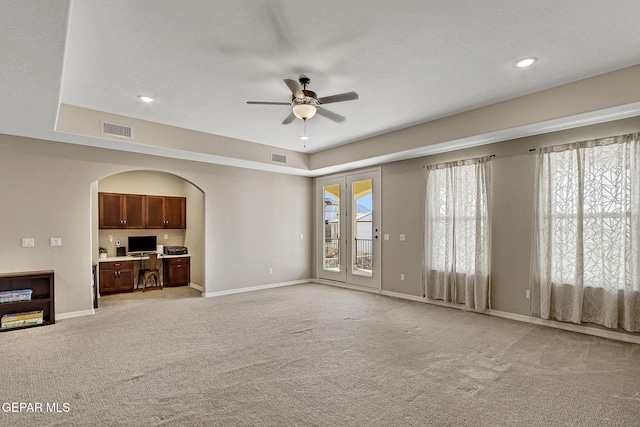 unfurnished living room featuring light carpet, visible vents, baseboards, and a ceiling fan