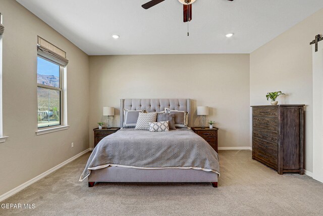 bedroom featuring light carpet, recessed lighting, a barn door, and baseboards