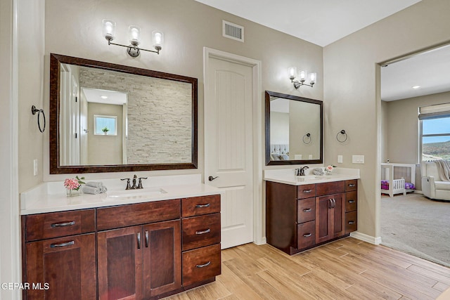 full bath with visible vents, vanity, baseboards, and wood finished floors