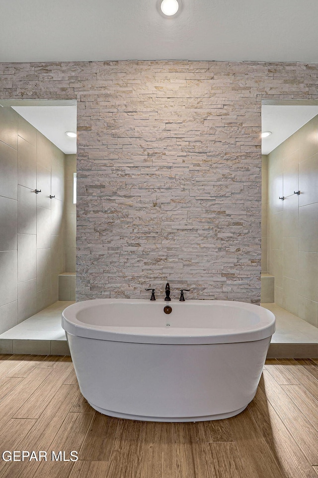 full bath featuring a soaking tub, walk in shower, and wood finished floors