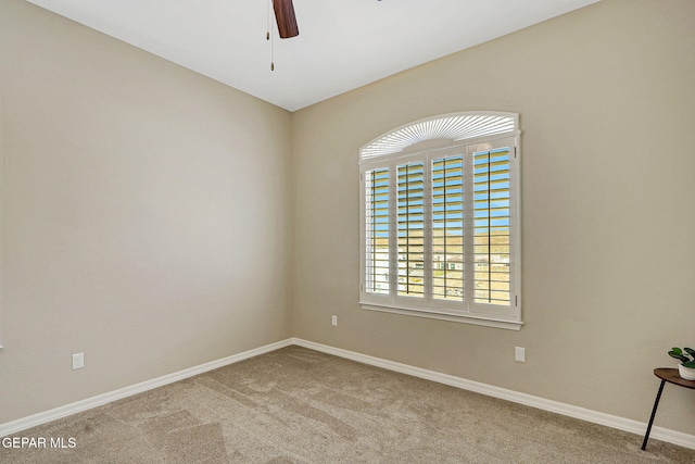 carpeted spare room with baseboards and a ceiling fan