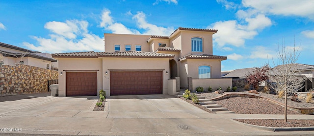 mediterranean / spanish house with concrete driveway, a tiled roof, a garage, and stucco siding