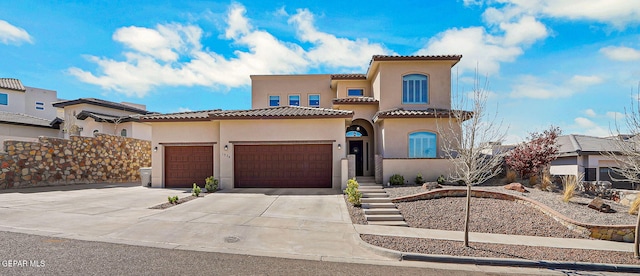 mediterranean / spanish home featuring a tiled roof, stucco siding, an attached garage, and concrete driveway