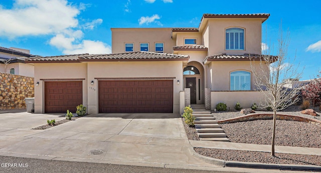 mediterranean / spanish-style home with stucco siding, concrete driveway, an attached garage, and a tiled roof