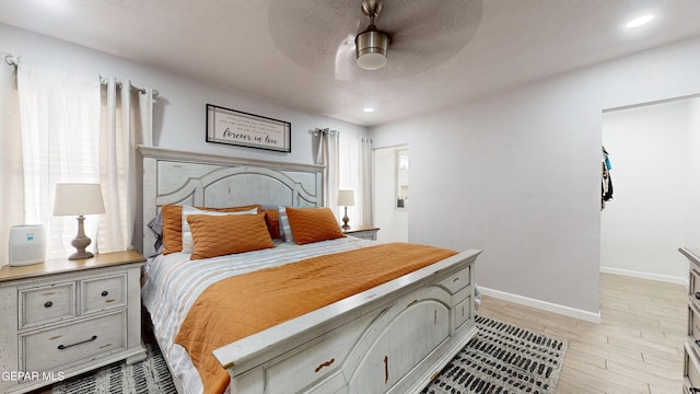 bedroom with ceiling fan, light hardwood / wood-style flooring, and a textured ceiling