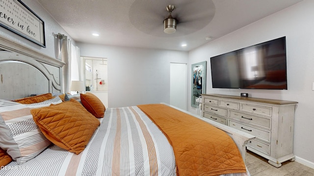 bedroom featuring a textured ceiling, a walk in closet, a closet, and ceiling fan