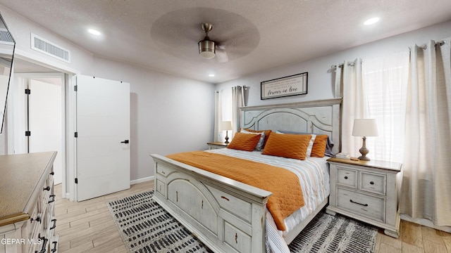 bedroom featuring ceiling fan, a textured ceiling, and light wood-type flooring