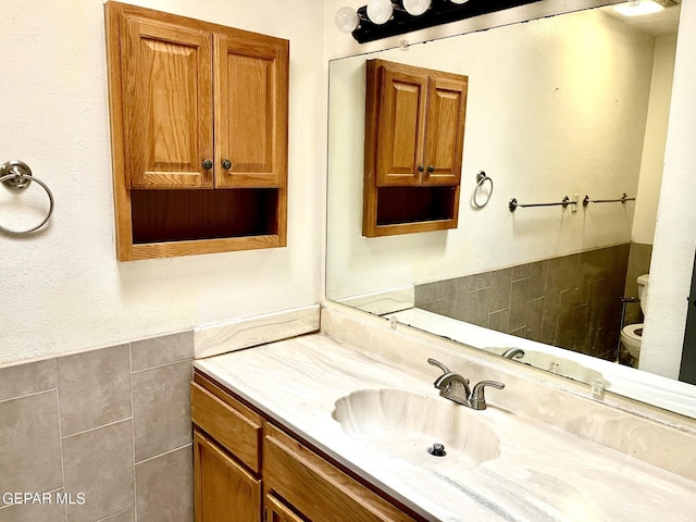 bathroom with vanity, tile walls, and toilet