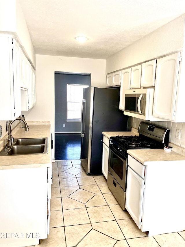 kitchen with white cabinets, tasteful backsplash, sink, and stainless steel gas range