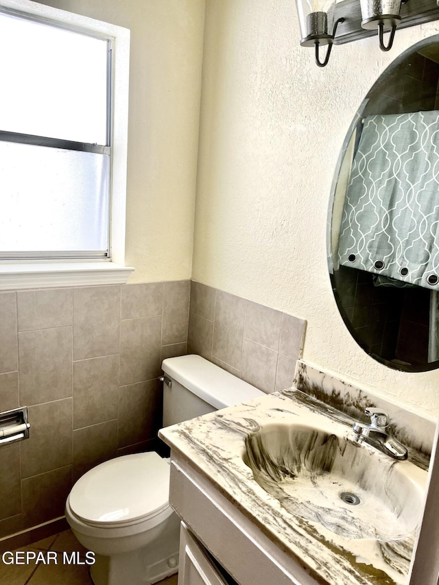 bathroom featuring vanity, toilet, and tile walls