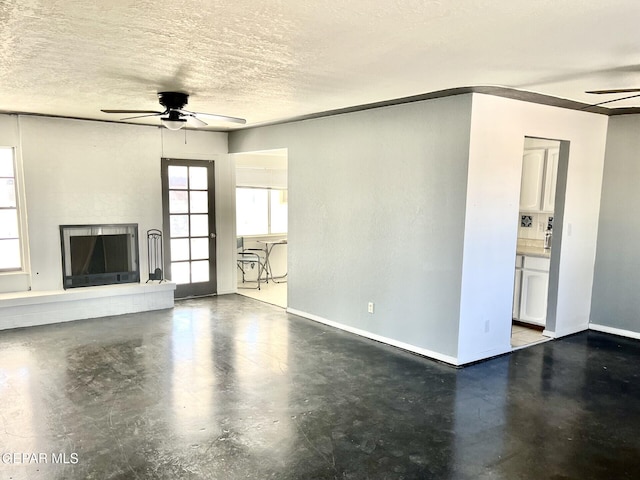 unfurnished living room featuring ceiling fan and a textured ceiling