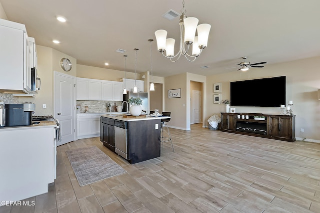 kitchen featuring sink, white cabinetry, a center island with sink, pendant lighting, and stainless steel appliances