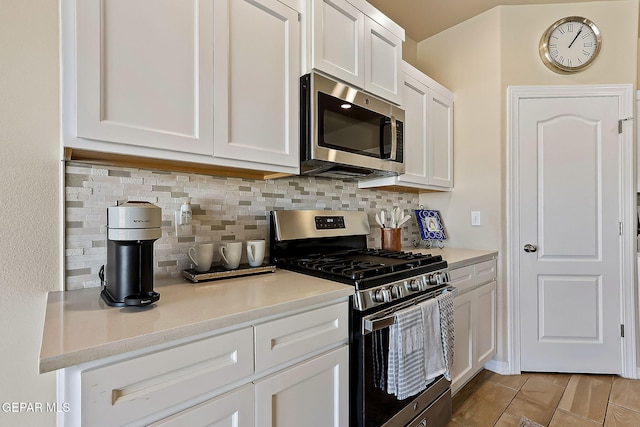 kitchen featuring backsplash, stainless steel appliances, white cabinets, and light stone countertops