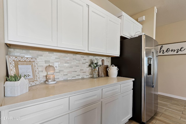 kitchen featuring white cabinetry, light hardwood / wood-style floors, stainless steel fridge with ice dispenser, and backsplash