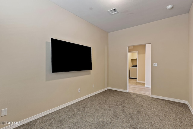 spare room featuring washer / dryer and light carpet