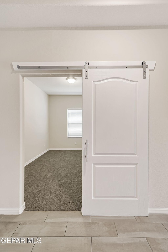 empty room with a barn door and light carpet