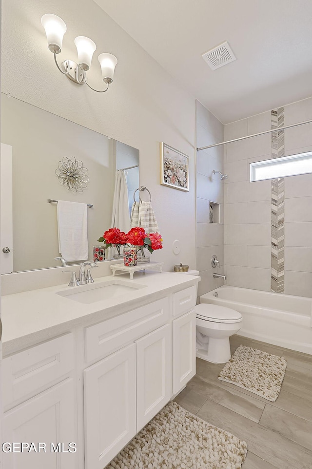 full bathroom featuring tiled shower / bath, vanity, and toilet