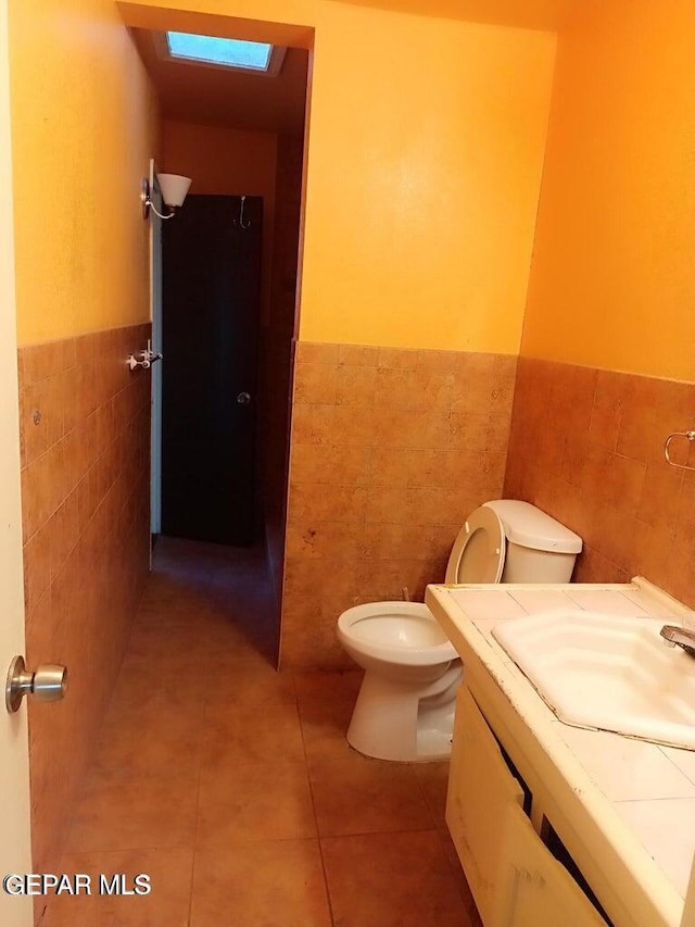 bathroom with vanity, toilet, tile patterned flooring, and tile walls